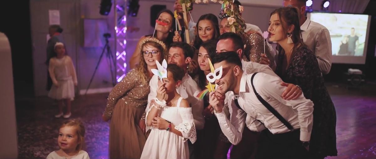 Des invités d’un mariage posent devant la borne BeSelfie avec des accessoires